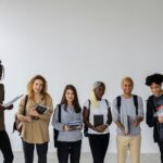 A group of cheerful, diverse college students posing together with books indoors.